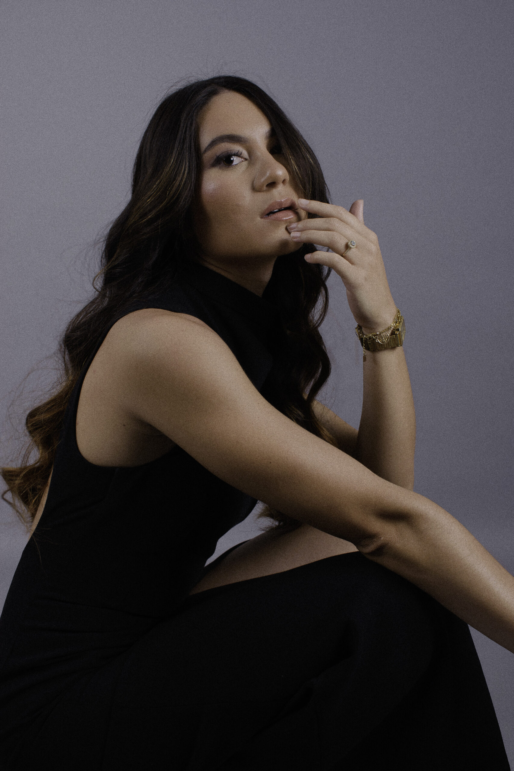 Portrait studio en couleur d’une femme assise, élégante et assurée
